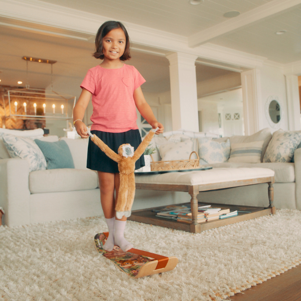Child balancing on a GIBBY Slackboard in a modern living room, while holding a GIBBY Plushy.